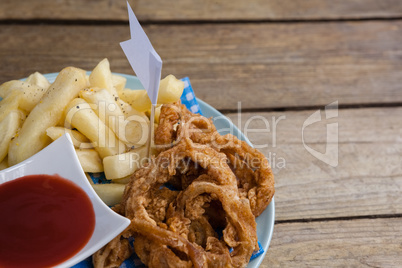 Onion ring and french fries with ketchup arranged in plate