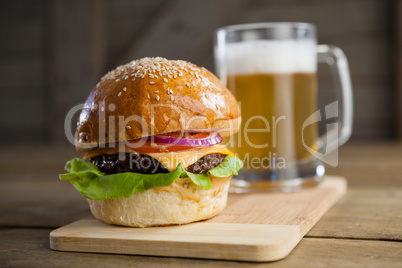 Burger with glass of beer on chopping board
