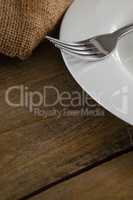 White plate and fork on wooden table