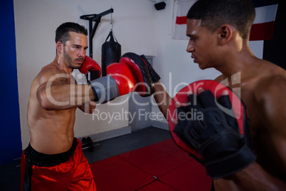 Trainer assisting man in boxing