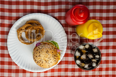 Hamburger, french fries, onion ring and cold drink on napkin