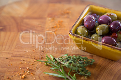 Marinated olives with herbs and chili in container on table