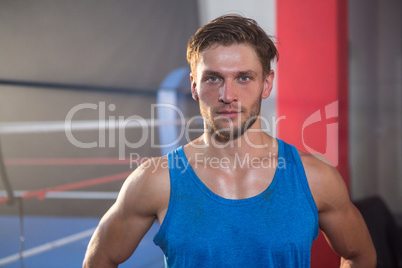 Portrait of young male athlete standing by boxing ring