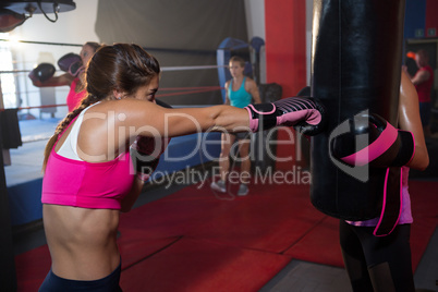 Young female boxer punching black bag