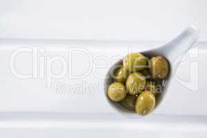 Marinated green olives in a spoon on table