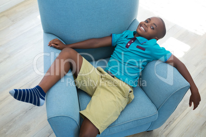 High angle portrait of boy lying on armchair at home