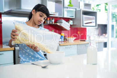 Girl pouring breakfast cereal in bowl