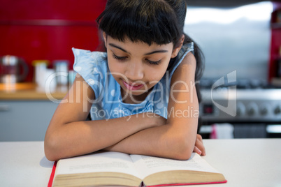 Girl with arms crossed reading novel at home
