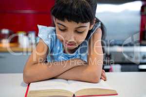 Girl with arms crossed reading novel at home