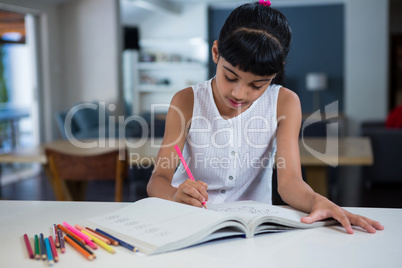 Girl drawing in book on counter