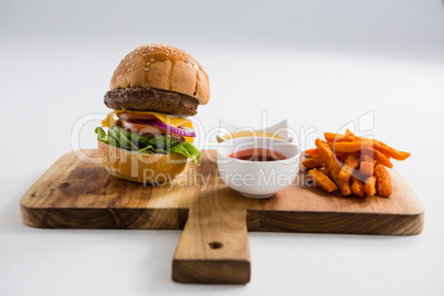 Dips with French fries and burger on cutting board