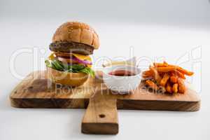 Dips with French fries and burger on cutting board