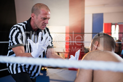 Referee gesturing to male boxer in ring