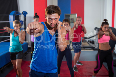 Young male and female athletes punching by boxing ring