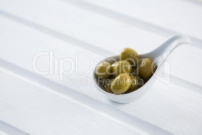 Marinated green olives in a spoon on table