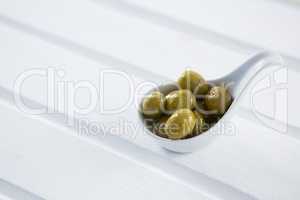 Marinated green olives in a spoon on table