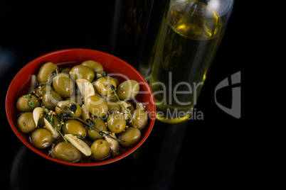 Close-up of marinated olives with olive oil and balsamic vinegar bottle
