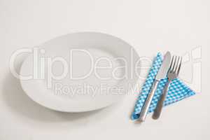 Empty plate with eating utensils and napkin