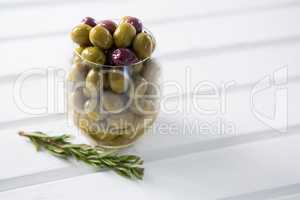Pickled olives with rosemary on wooden table