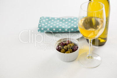 Close-up marinated olives with glass and bottle of wine