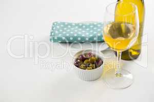 Close-up marinated olives with glass and bottle of wine