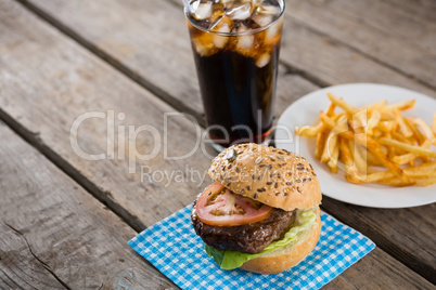 Hamburger on napkin with french fries in table by drink