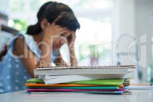 Stack of books against girl with head in hands