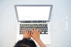 High angle view of girl typing on laptop with blank screen