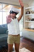 Girl using virtual reality simulator while standing in living room