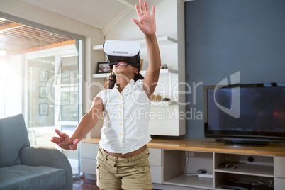 Happy girl using virtual reality simulator while standing in living room