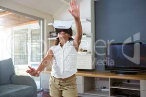 Happy girl using virtual reality simulator while standing in living room