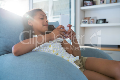 Girl using digital tablet while sitting on armchair