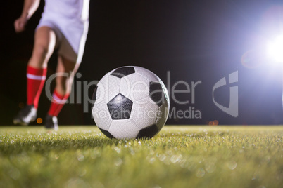 Low section of soccer player and ball on field