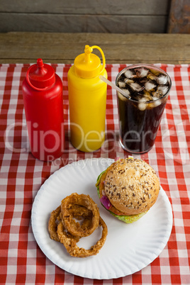 Hamburger, french fries, onion ring and cold drink on napkin