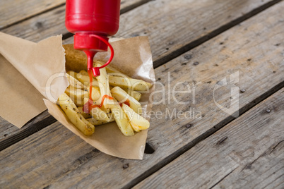 High angle view of bottle pouring sauce on French fries