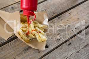 High angle view of bottle pouring sauce on French fries