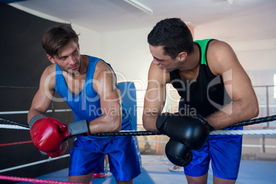 Young male boxers leaning on rope