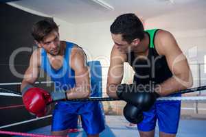 Young male boxers leaning on rope