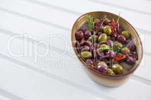 Pickled olives with herbs and chili in bowl on table