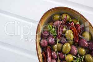 Pickled olives with herbs and chili in bowl on table