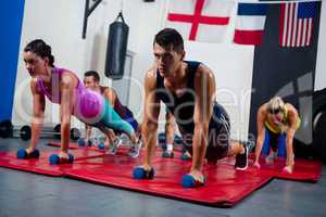 Young athletes practicing push ups on dumbbells