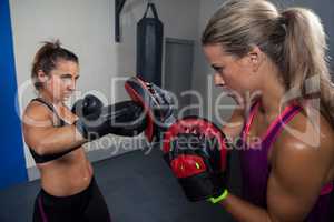 Trainer assisting woman in boxing