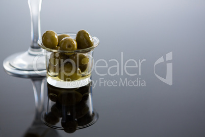 Glass with olives on table