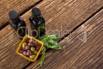 Pickled olives with herbs and balsamic vinegar bottles on table