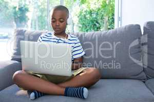 Boy using laptop while listening to headphones at home