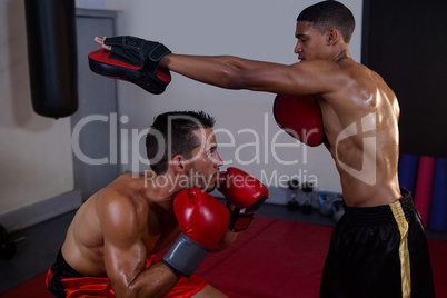 Trainer assisting man in boxing