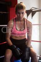 Portrait of confident woman sitting in boxing ring