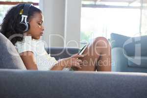 Side view of girl listening music while using tablet computer