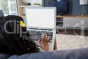 Rear view of girl using laptop at home