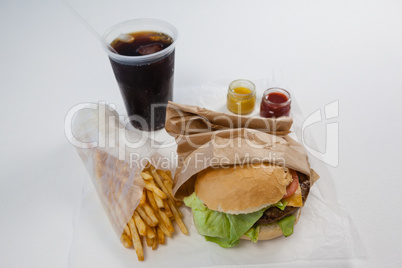 Close-up of hamburger, french fries, sauce and cold drink